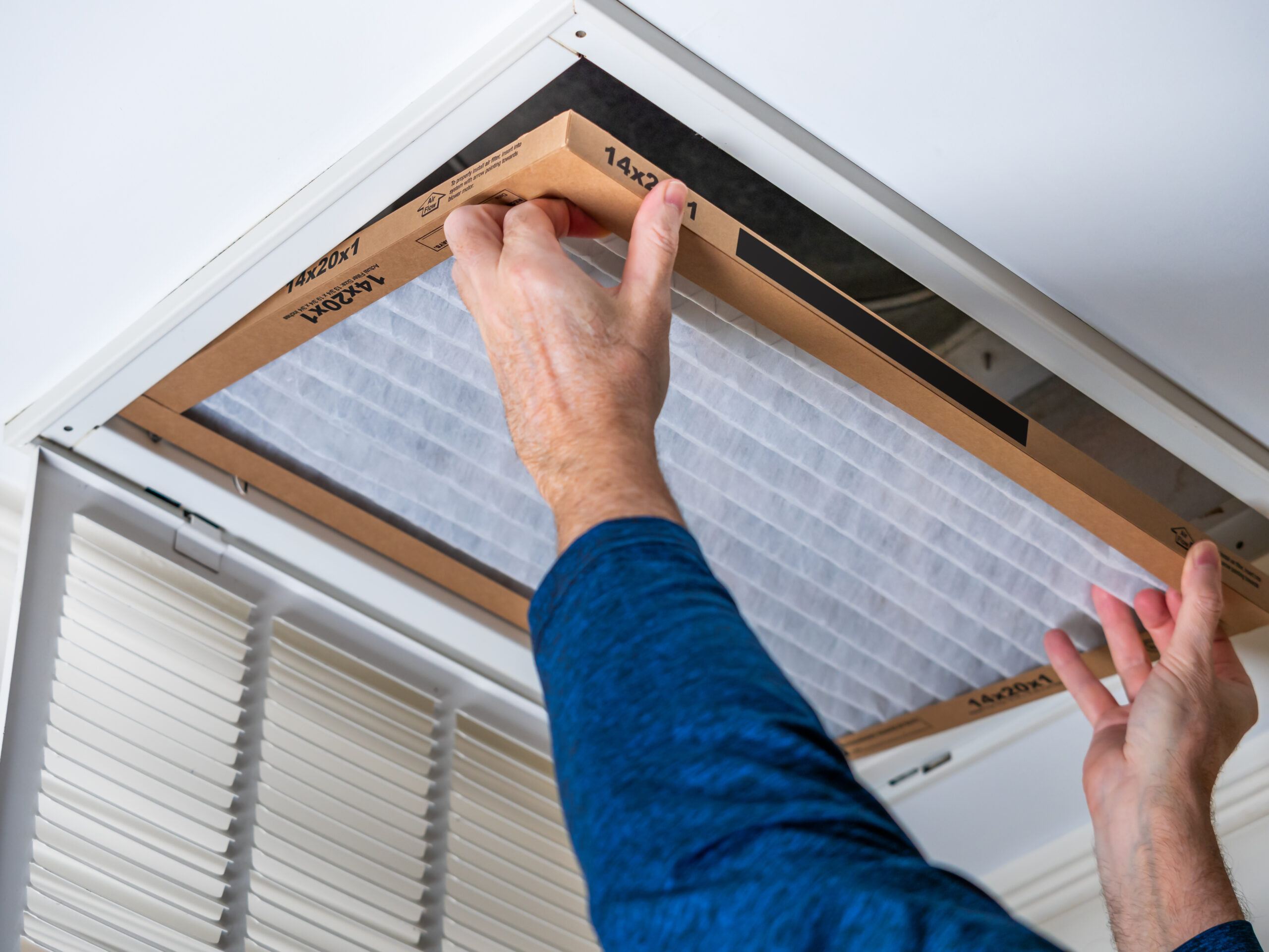 Man replacing dirty HVAC air filter in ceiling vent. Home air du